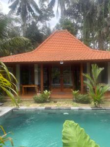 a house with an orange roof next to a swimming pool at Dewaka Villa in Ubud +18 photos