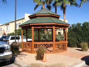a wooden gazebo with a green roof in a parking lot at Brawley Inn in Brawley