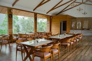 a restaurant with wooden tables and chairs and windows at The TeaTree Munnar in Suryanelli