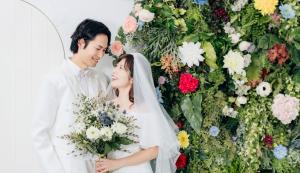 网走市Tabist Abashiri Central Hotel的站在花卉墙前的新娘和新郎