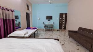 a room with two beds and a table and a couch at LD Guest House, Ayodhya in Ayodhya