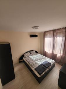 a bedroom with a bed and a large window at Уютен Апартамент in Sofia