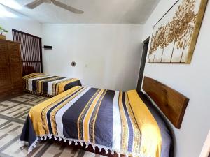two beds in a room with white walls at Casa Guiba 2 Puerto Escondido in Puerto Escondido