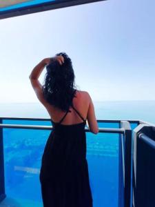 巴统Special Sea View Aparthotel In Orbi City的一位身穿黑色连衣裙的女子凝视着大海