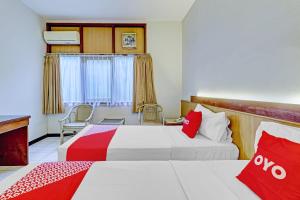 a hotel room with two beds with red and white at Collection O Riau Near Trans Studio Bandung Formerly Asteria Hotel in Bandung