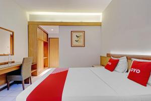 a hotel room with a bed with red pillows and a desk at Collection O Riau Near Trans Studio Bandung Formerly Asteria Hotel in Bandung