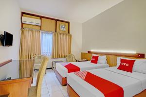 a hotel room with two beds and a television at Collection O Riau Near Trans Studio Bandung Formerly Asteria Hotel in Bandung +33 photos