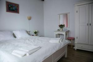 um quarto com uma cama branca e toalhas em Pensiunea Margareta em Budeasa Mică