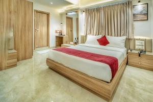 Un dormitorio con una cama grande con almohadas rojas. en Hotel The Grand Murli, en Surat