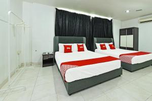 a bedroom with two beds with red pillows at Hotel O Gemilang in Kuala Terengganu