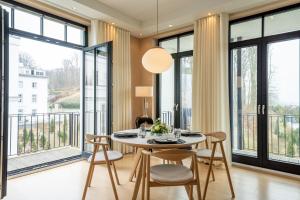 a dining room with a table and chairs and large windows at Villa Philine - Meerblick-Appartement 27 "Arwen" in Ostseebad Sellin