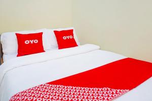 two red pillows on a bed in a room at Flagship 90723 Berlima Guest House Syariah in Malang