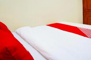 a bed with red and white sheets on it at Flagship 90723 Berlima Guest House Syariah in Malang +22 photos