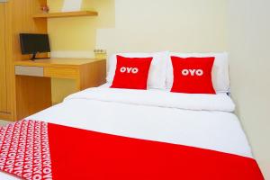 a red and white bed with two red pillows on it at Flagship 90723 Berlima Guest House Syariah in Malang