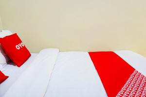 a bed with red and white ties on it at Flagship 90723 Berlima Guest House Syariah in Malang