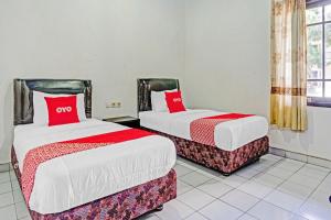 two beds with red pillows in a room at Hotel O Palem Garden 2 in Tulungagung +17 photos