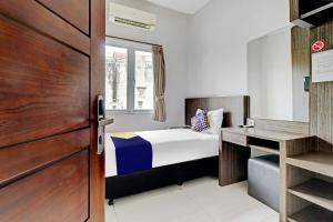 a small bedroom with a bed and a desk at Hotel O Cihampelas Near Ciwalk Formerly D'River Guest House in Bandung
