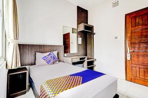 a bedroom with a bed and a wooden door at Hotel O Cihampelas Near Ciwalk Formerly D'River Guest House in Bandung