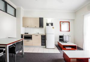 a kitchen with a refrigerator, stove, microwave and a table at Novotel Darwin Airport in Darwin