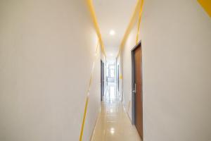 a hallway with white walls and wooden floors and a long corridor at Collection O Millenium Inn 2 in Medan +27 photos