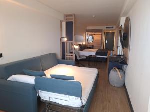 a living room with a blue couch and a bedroom at Sercotel Playa Canteras in Las Palmas de Gran Canaria