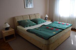 a bedroom with a bed with green sheets and pillows at Bibinje Apartment in Bibinje