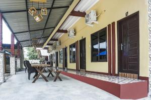 a patio with a table and chairs and a building at Hotel O Penginapan Dafandra Beach Near Pantai Tanjung Bira in Bira