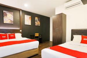 a hotel room with two beds with red pillows at Hotel O Kl2f Rest & Go in Shah Alam