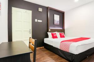 a bedroom with a bed with red pillows and a table at Hotel O Kl2f Rest & Go in Shah Alam