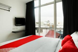 a bedroom with a red and white bed and a window at Hotel O Kl2f Rest & Go in Shah Alam