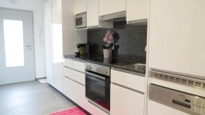 a kitchen with white cabinets and a stove top oven at Apartement Maria Trost in Graz