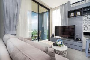 a living room with a couch and a flat screen tv at Tropics Kamala Residence CTG L709, Several Pools, near Phuket Fantasea & Beach in Kamala Beach