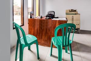 two green chairs sitting in front of a desk at OYO Homes 91067 Desa Wisata Santanamekar in Rajapolah