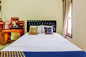 a bedroom with a large bed and a desk at OYO Homes 91067 Desa Wisata Santanamekar in Rajapolah