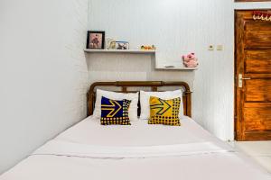 a bedroom with a bed with yellow and blue pillows at OYO Homes 91067 Desa Wisata Santanamekar in Rajapolah