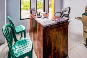 an office with a desk and two green chairs at OYO Homes 91067 Desa Wisata Santanamekar in Rajapolah