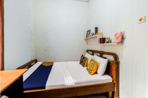 a small bedroom with a bed with yellow and blue pillows at OYO Homes 91067 Desa Wisata Santanamekar in Rajapolah