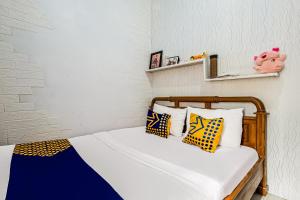a bedroom with a bed with yellow and blue pillows at OYO Homes 91067 Desa Wisata Santanamekar in Rajapolah