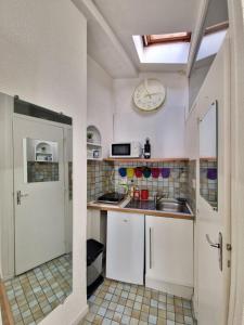 een keuken met een wastafel en een klok aan de muur bij Le Massillon #Hypercentre in Clermont-Ferrand