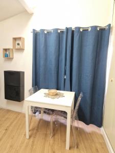 een tafel en een blauw gordijn in een kamer bij Le Massillon #Hypercentre in Clermont-Ferrand +1 foto