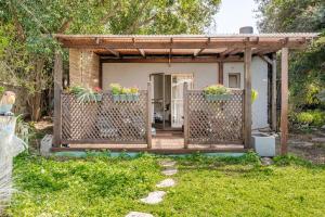 een klein huis met een houten veranda met potplanten bij Cozy Givat Ada Countryside Stay in Giv‘at ‘Ada