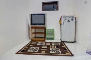 a room with a television and a rug next to a refrigerator at Hotel O Desa Wisata Kawasen in Padaherang
