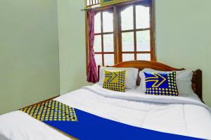 a bed with blue and yellow pillows and a window at OYO Homes 91154 Desa Wisata Wayang Manyaran Wonogiri in Wonogiri