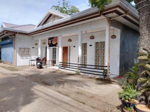 a white house with a tree in front of it at R & J Homestay in Naga Cebu in Tina-an