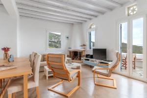 a living room with a table and chairs and a television at Vassilis Family Villa Tinos in Triandáros