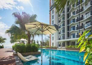 a swimming pool with an umbrella next to a building at Nature Home 3 - Swiss Garden Resort Residences in Kampung Sungai Karang