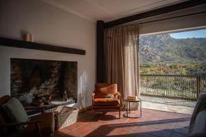 a living room with a fireplace and a chair and a window at Stayatdestraadt Red Fin Cottage in Op-die-Berg