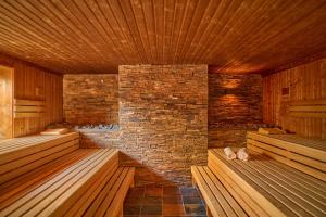 a sauna with wooden benches and a brick wall at Naturresort & Spa Schindelbruch in Stolberg