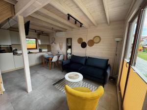 ein Wohnzimmer mit einer blauen Couch und einer Küche in der Unterkunft Koralia Domki i Apartamenty Basen z podgrzewaną wodą in Sarbinowo