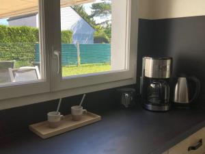 a kitchen counter with three coffee mugs and a window at Les volets verts in Le Crotoy